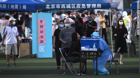 A health worker in a protective suit takes a swab test from a woman at a test center set up for people who have visited or live near Xinfadi Market in Beijing.