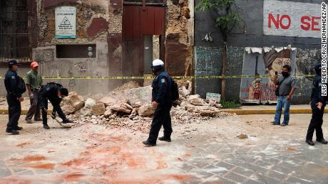 A police officer is removing trash from a building damaged in the earthquake in Oaxaca, Mexico.