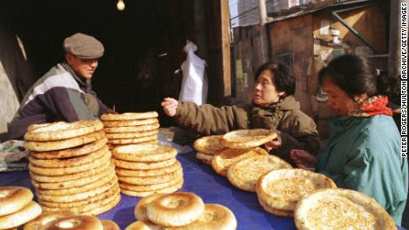 A Uyghur man sells traditional flat bread to women shoppers along Beijing’s Xinjiang Street in 1999.