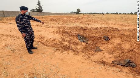 A member of the security forces linked to the Libyan government of the National Agreement (GNA), the Interior Ministry, points to the reported location of a mass grave in the city of Tarhuni, about 65 kilometers southeast of the capital Tripoli on June 11, 2020. 