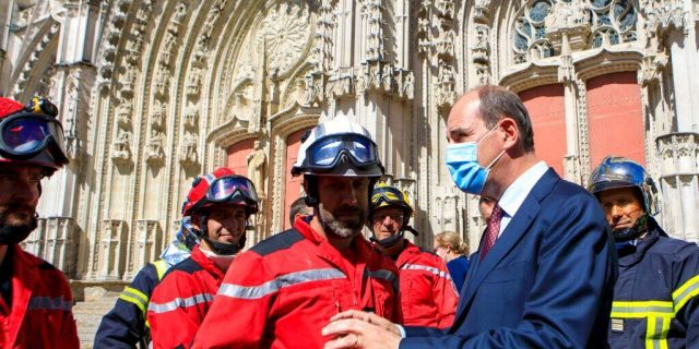 French Prime minister Jean Castex, right, wearing a face mask meets firefighters after the blaze at the Gothic St. Peter and St. Paul Cathedral, in Nantes, western France, Saturday, July 18, 2020. 