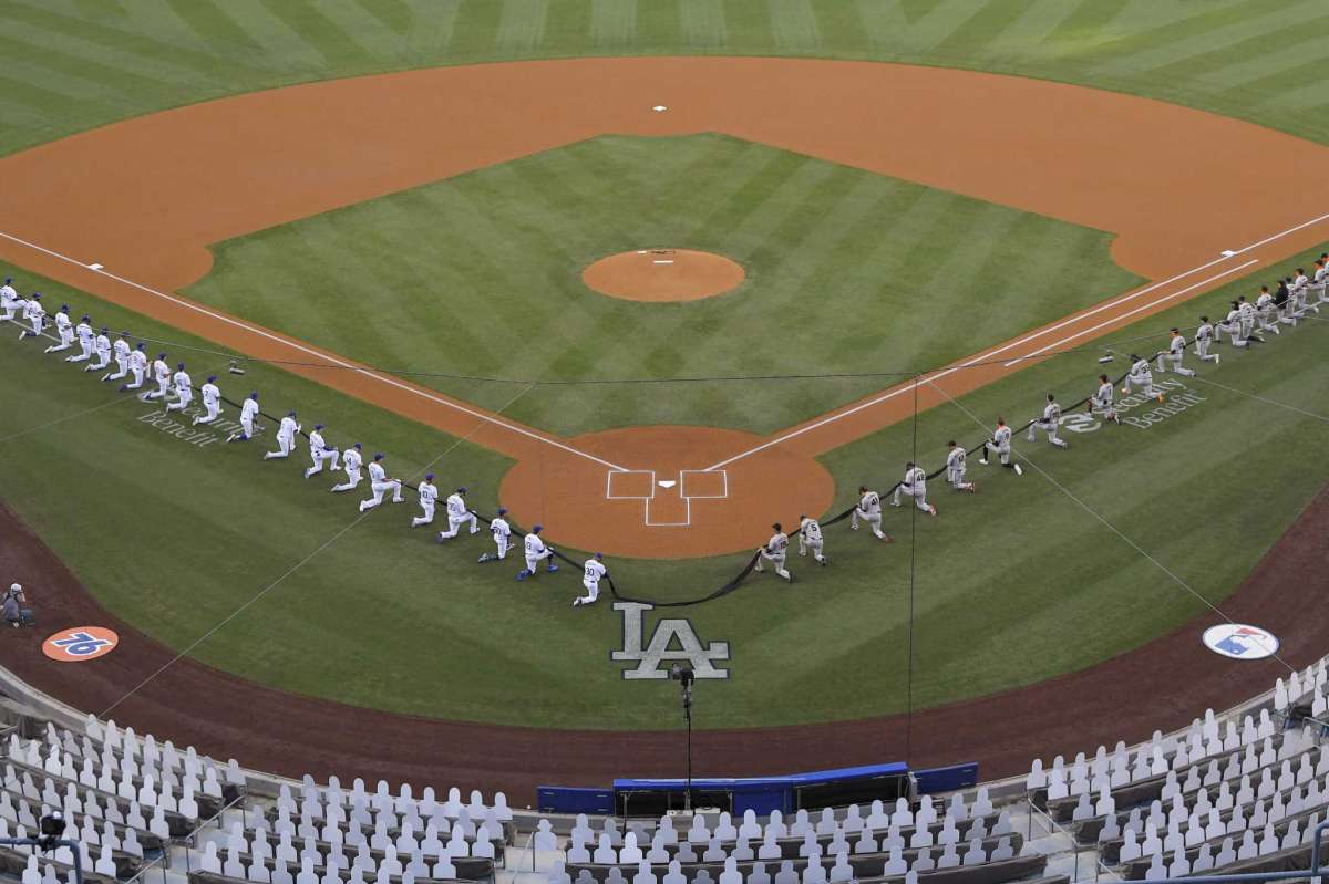 Members of the Los Angeles Dodgers and the San Francisco Giants kneel during a moment of silence prior to an opening day baseball game Thursday, July 23, 2020, in Los Angeles.