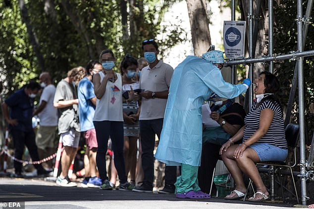 Pictured: Motorists wait in line for their swab samples to be taken for COVID-19 testing by health workers at the drive-in of the San Giovanni hospital in Italy as recommended by the Ministry of Health for all of those who returned from areas considered at risk