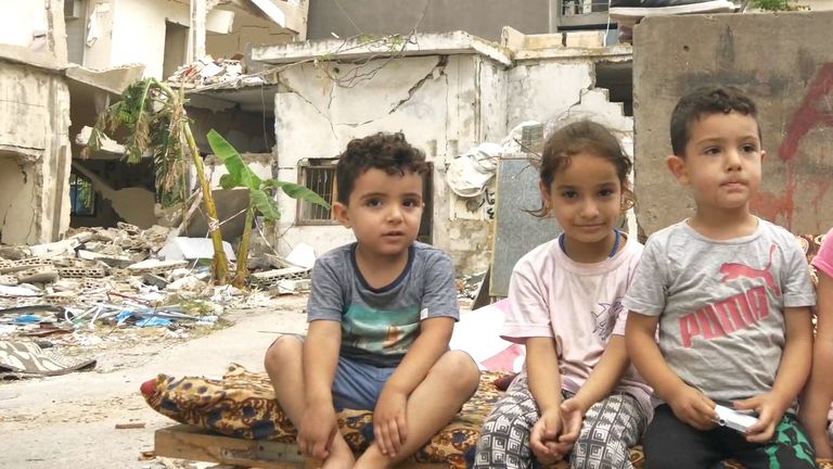 A Syrian refugee family sits on the rubble of their destroyed building in Beirut