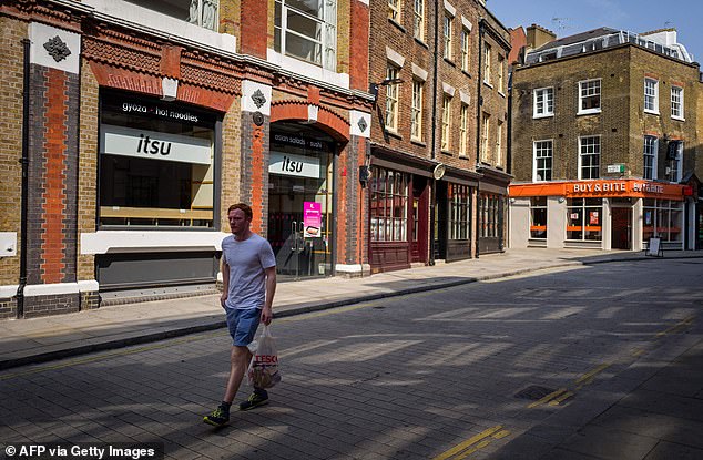 A pedestrian passes through shops and food outlets on an empty shopping street in London on August 12th