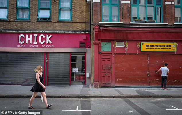 A pedestrian passes by closed storefronts on an empty London shopping street last month