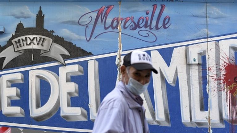 A man wearing a face mask walks past graffiti in Marseille