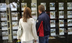 Young men are looking at the real estate agent window