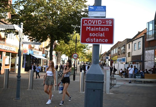 People walk by a sign encouraging social distancing on one of Solihull's shopping streets