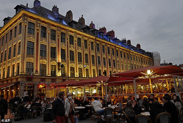 People enjoy a drink on the balcony of a restaurant in Lille, northern France, before curfew in the city