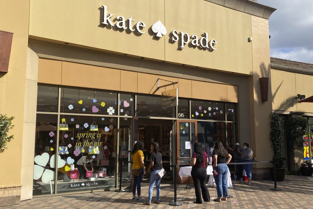 People wait outside of the Kate Spade store at the Citadel Outlets amid the global coronavirus COVID-19 pandemic, Friday, May 29, 2020, in Los Angeles. (Kirby Lee via AP)