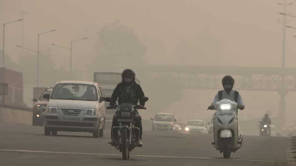 Commuters on NH-48 amid smog in Gurugram on Sunday.