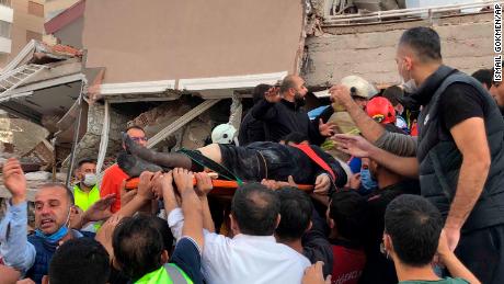 Rescue workers and locals carry a wounded man found in the rubble of a collapsed building in Izmir, Friday.