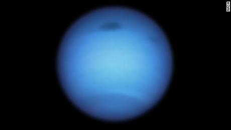 A Hubble Space Telescope snapshot of Neptune reveals a massive dark storm (top center) and a smaller, nearby dark spot (top right). 