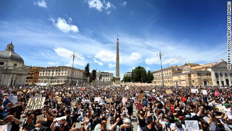 Protesters kneel holding placards in Rome.