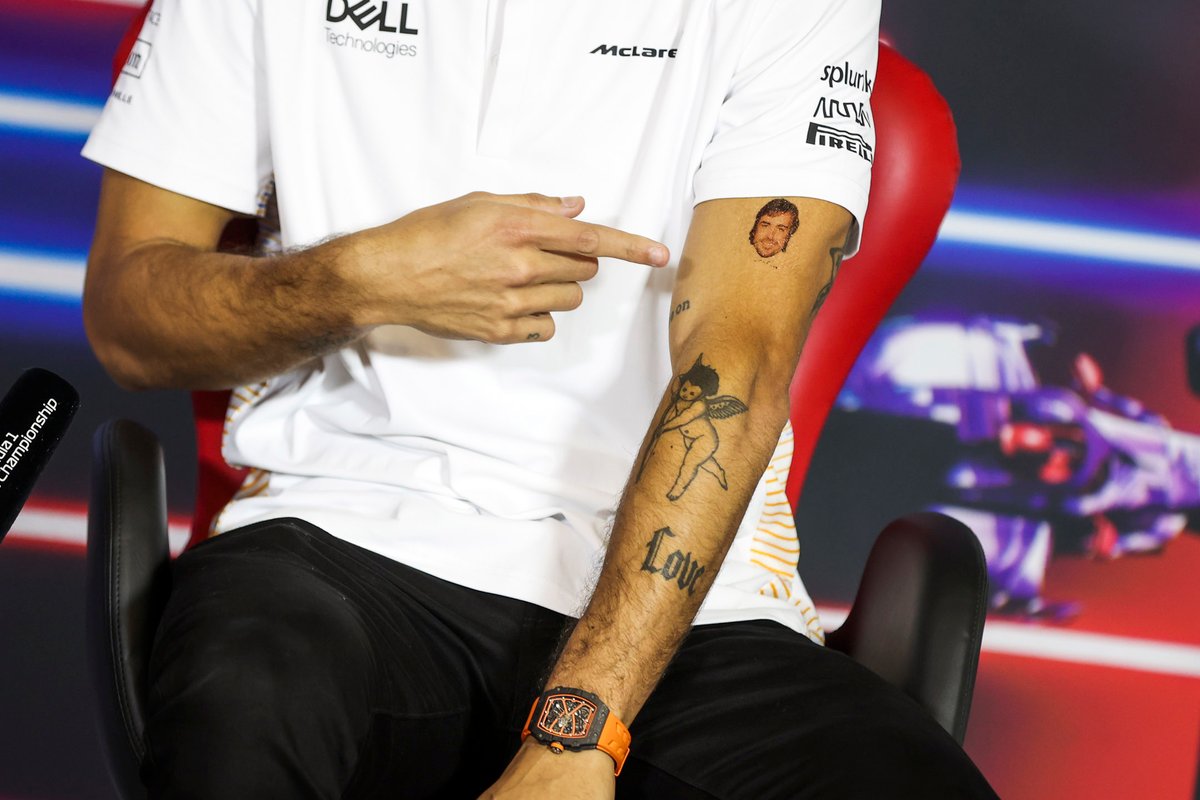 Daniel Ricciardo, McLaren, points to a temporary tattoo of Fernando Alonso, Alpine F1